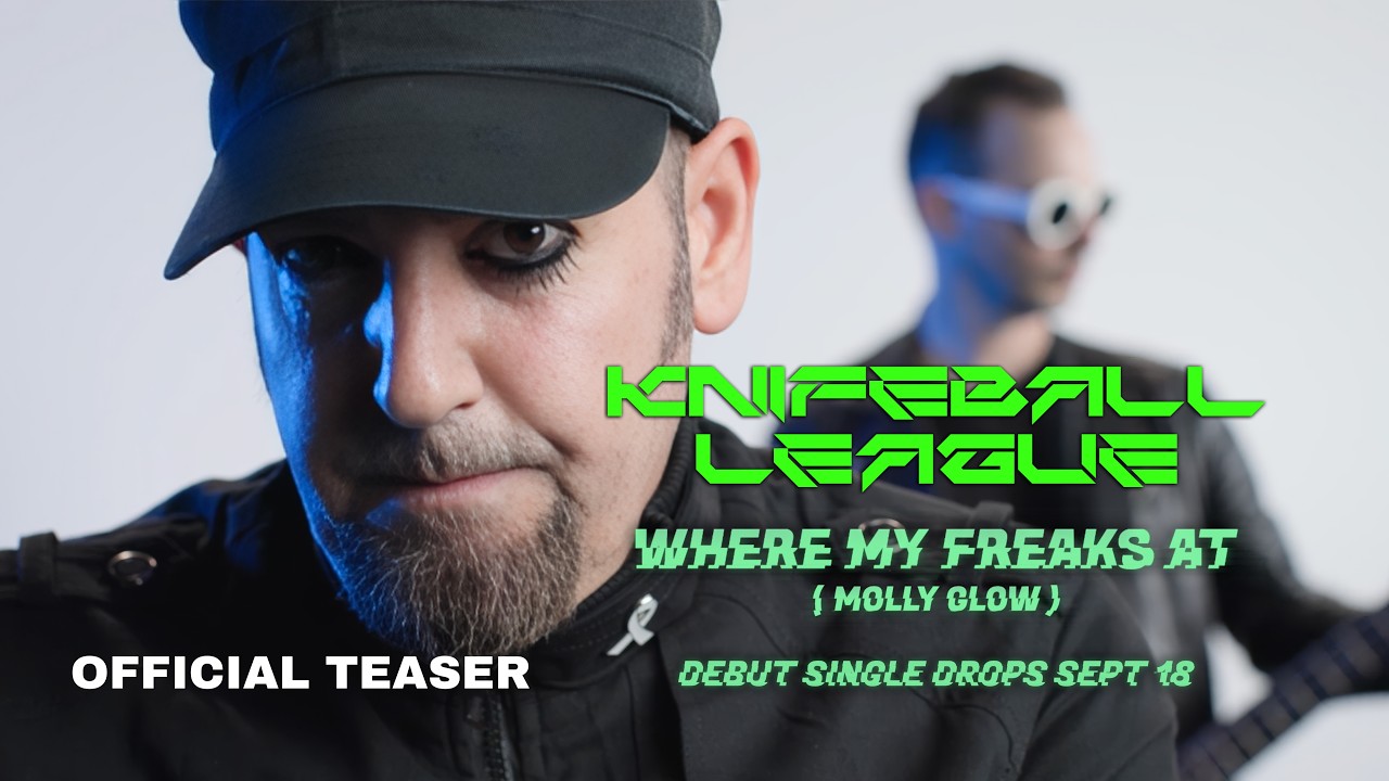 Knifeball League — a close-up of a bearded man in a dark military cap lit blue, with a second band member out of focus behind him in round white goggles, holding a guitar. Green lettering reads Knifeball League, Where My Freaks At (Molly Glow), debut single drops Sept 18, and the corner is marked Official Teaser.